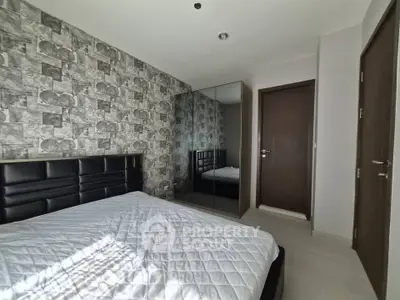 Modern bedroom with stylish wallpaper and mirrored wardrobe in a cozy apartment.