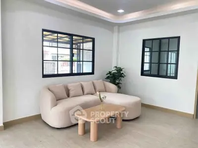 Modern living room with stylish beige sofa and wooden coffee table, featuring large windows and elegant decor.