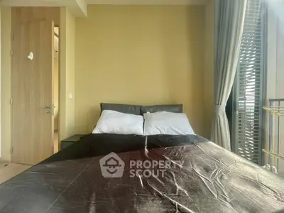 Modern bedroom with large window and balcony access, featuring a cozy bed and stylish decor.
