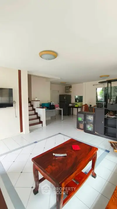 Spacious living room with modern decor and open layout, featuring a wooden coffee table and staircase.