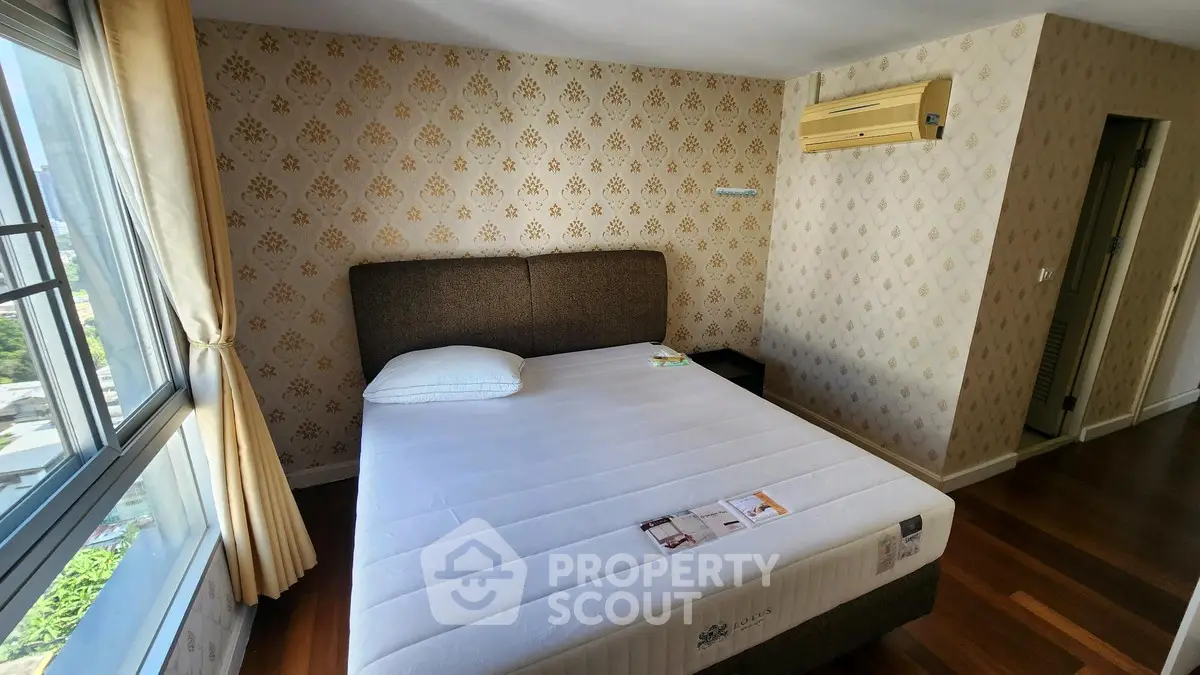 Cozy bedroom with elegant wallpaper and large window offering city views