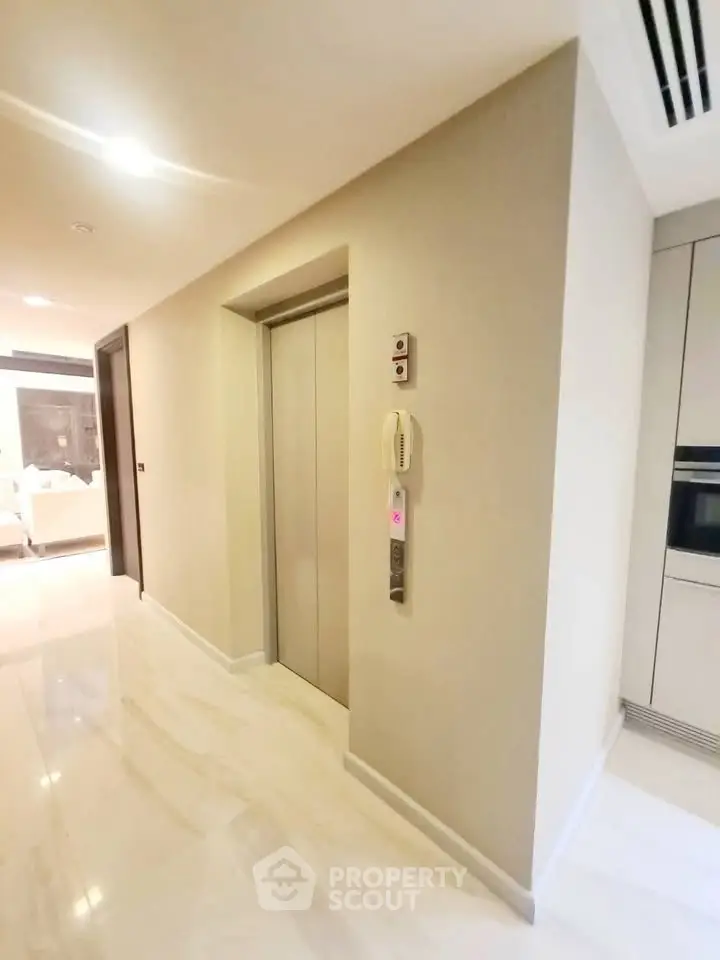 Modern apartment hallway with sleek elevator access and polished flooring.