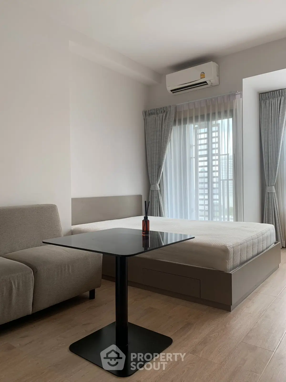 Modern bedroom with sleek furniture and natural light, featuring a cozy bed and stylish sofa.