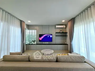 Modern living room with sleek design, large windows, and a wall-mounted TV for ultimate comfort.