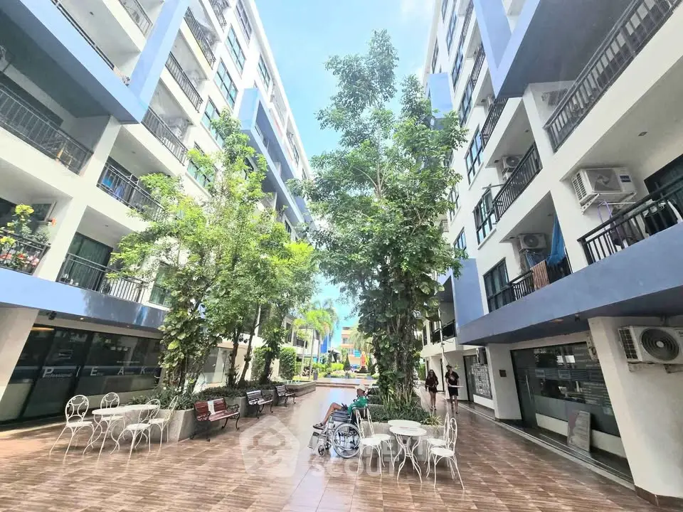 Modern apartment complex courtyard with lush greenery and seating area