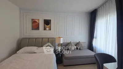 Modern bedroom with stylish decor and cozy seating area, featuring elegant wall art and natural light.