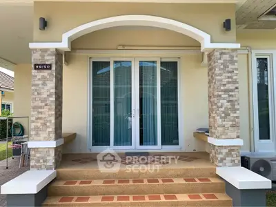 Charming house entrance with elegant stone columns and inviting double doors, perfect for a warm welcome.