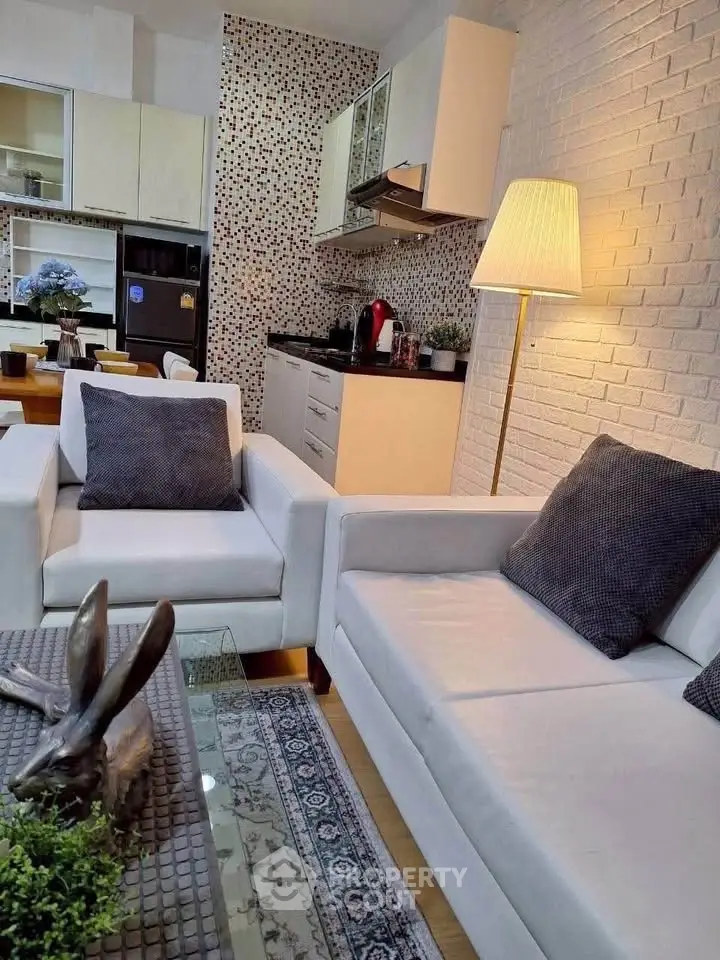 Modern living room with stylish kitchen, featuring white sofas and mosaic backsplash.