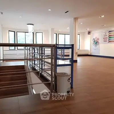 Spacious modern interior with large windows and sleek railing, ideal for office or commercial use.