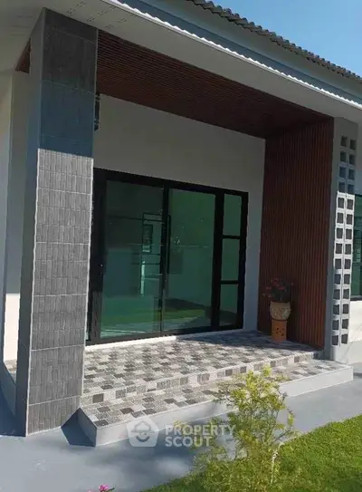Modern house exterior with stylish entrance and glass doors, featuring a sleek design and inviting ambiance.