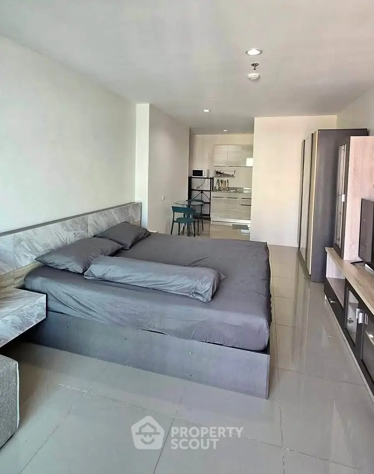 Modern studio apartment with sleek design and open layout, featuring a cozy bed and stylish kitchen area.