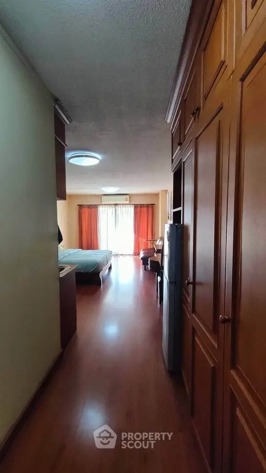 Spacious bedroom with wooden flooring and large wardrobe, featuring natural light from balcony.