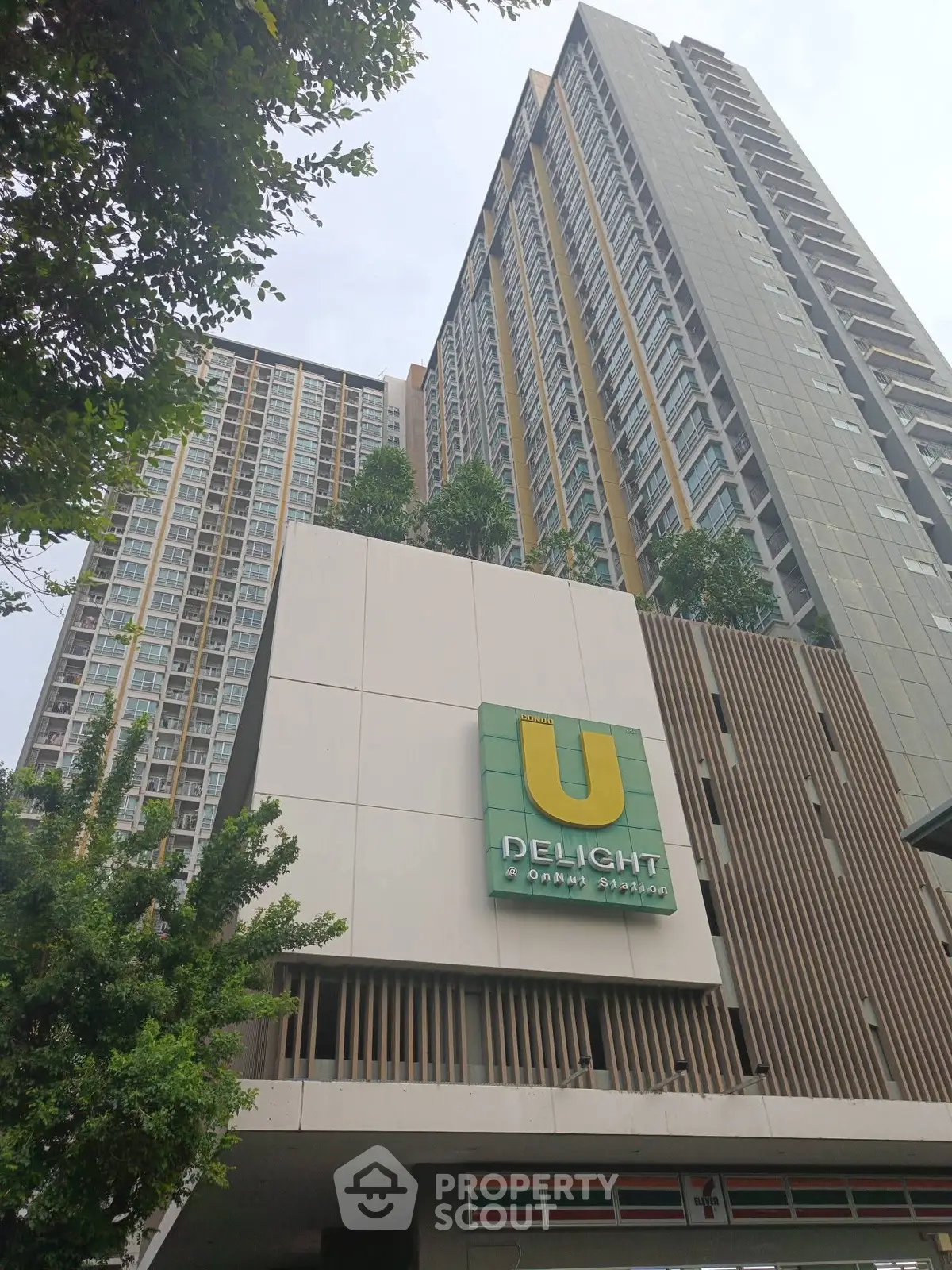 Modern high-rise building with lush greenery and prominent signage.