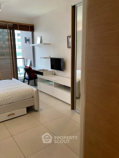 Modern bedroom with sleek design, featuring a cozy bed, wall-mounted TV, and a study desk by the window.