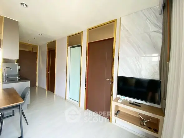Modern apartment interior with sleek kitchen and cozy living area featuring a wall-mounted TV.