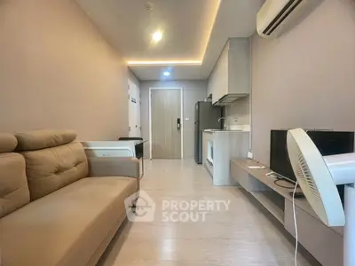 Modern living room with sleek design, featuring a comfortable sofa, air conditioning, and a compact kitchen area.
