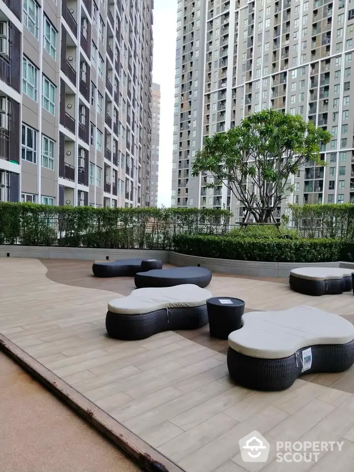 Modern apartment complex with stylish outdoor seating area and lush greenery.