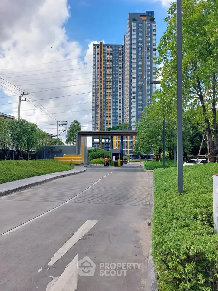 Modern high-rise building with lush greenery and clear blue sky, showcasing urban living at its finest.