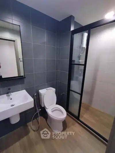 Modern bathroom with sleek design, featuring a glass shower enclosure and contemporary fixtures.