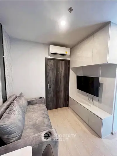 Modern living room with sleek furniture and wall-mounted TV in a compact space.