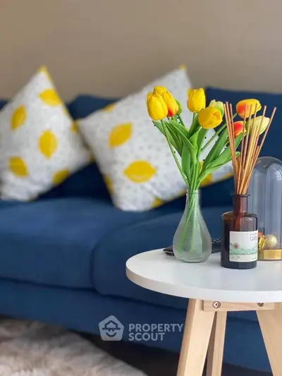Chic living room with blue sofa, vibrant cushions, and elegant decor on a stylish side table.