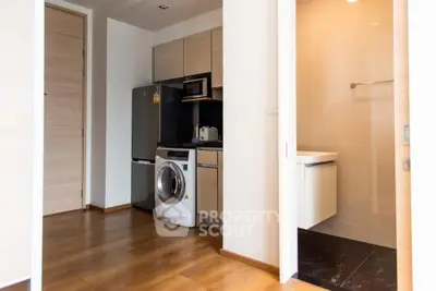 Modern apartment with sleek kitchen and laundry area, featuring wooden flooring and contemporary design.