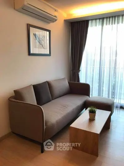 Modern living room with cozy sofa, stylish decor, and natural light from large window.
