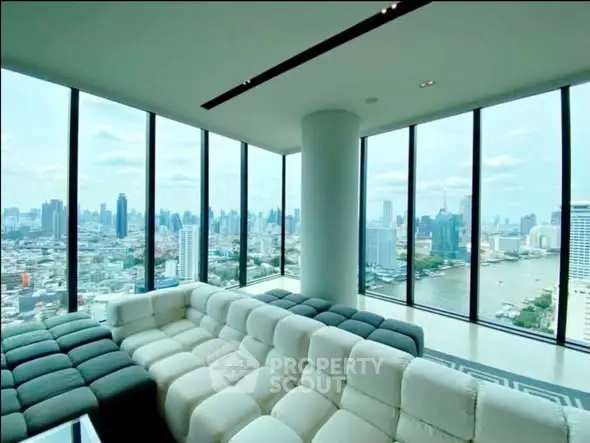 Luxurious living room with panoramic city and river views, featuring modern furniture and floor-to-ceiling windows.