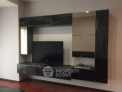 Modern living room with sleek black entertainment center and flat-screen TV.