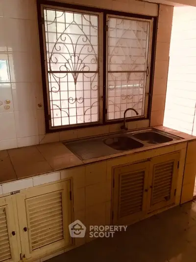 Charming kitchen with vintage sink and window grills, perfect for cozy home cooking.