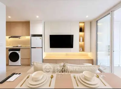 Modern open-plan living room with kitchen, featuring sleek appliances and elegant dining setup.
