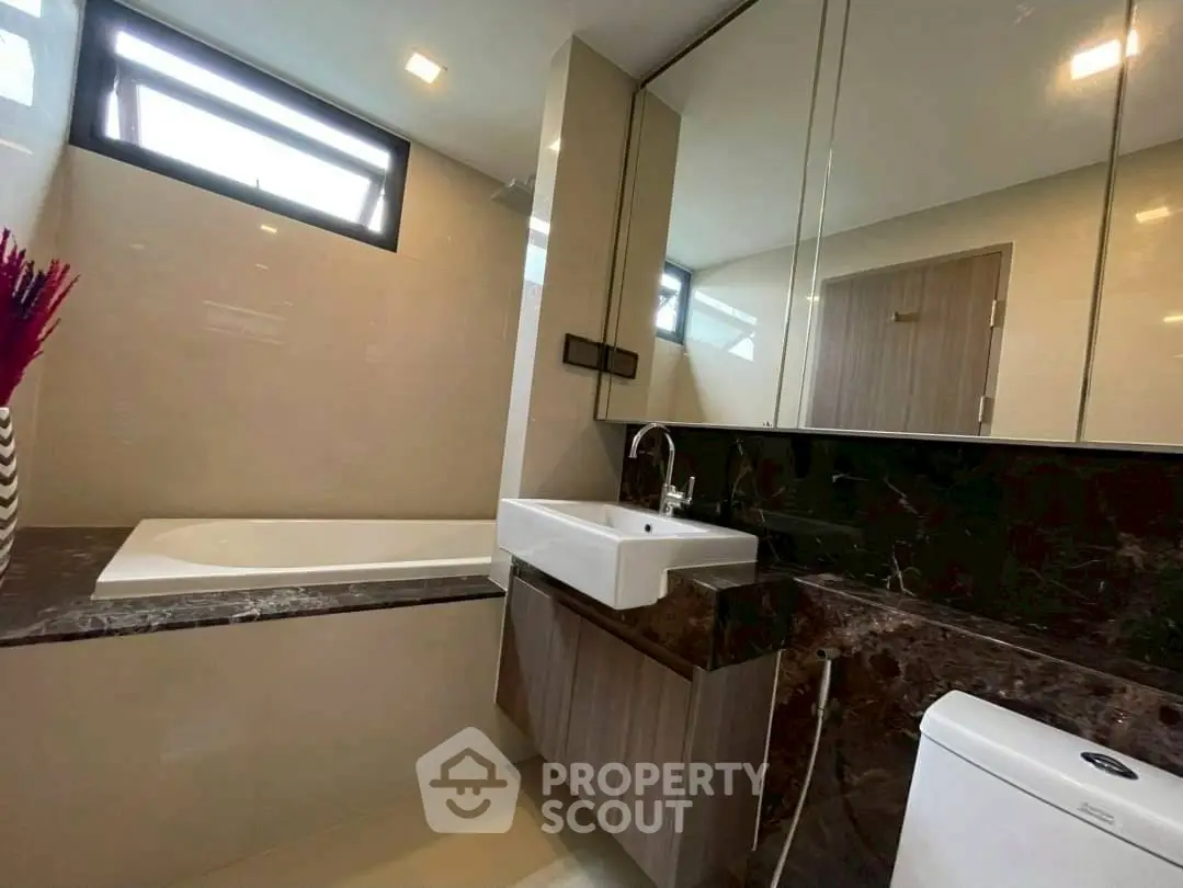 Modern bathroom with sleek design, featuring a bathtub and stylish vanity.