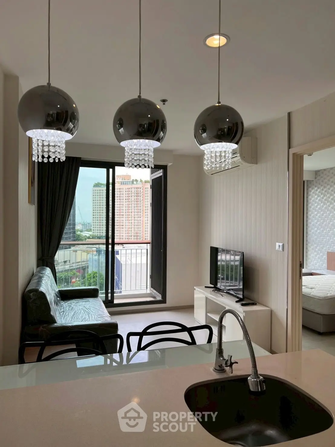 Modern open-plan living room with stylish lighting and balcony view in a high-rise apartment.