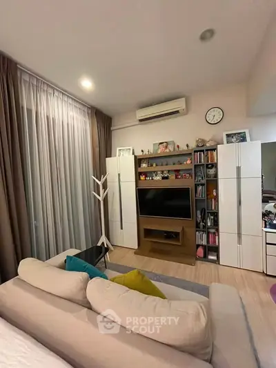 Cozy living room with modern decor, featuring a plush sofa, entertainment center, and stylish shelving.
