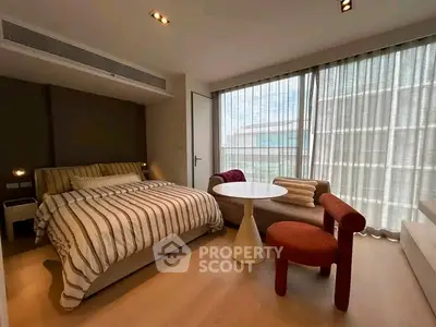 Modern bedroom with stylish furniture and large windows offering natural light.