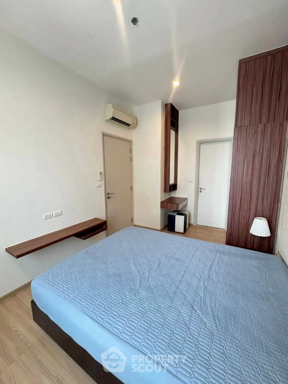 Modern bedroom with sleek wooden furniture and air conditioning in a stylish apartment.