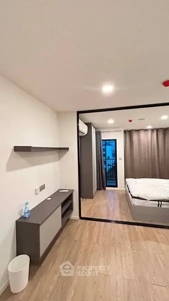 Modern bedroom with wooden flooring and large window view