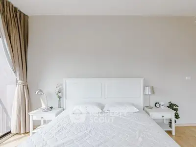 Bright and airy bedroom with elegant white furnishings and large window view.