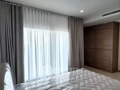Modern bedroom with large window and stylish curtains, featuring a sleek wardrobe.