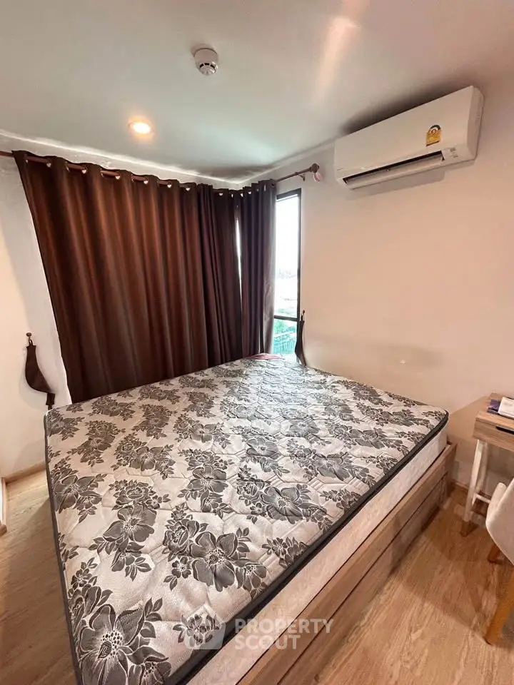 Cozy bedroom with large bed and air conditioning, featuring elegant curtains and wooden flooring.
