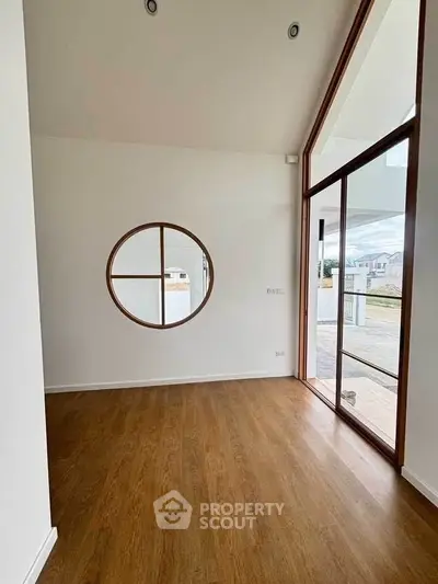 Modern minimalist room with circular window and wooden flooring