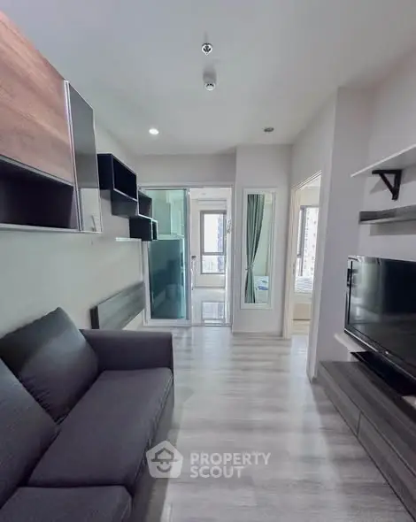 Modern living room with sleek design and large TV, featuring stylish shelving and a cozy sofa.