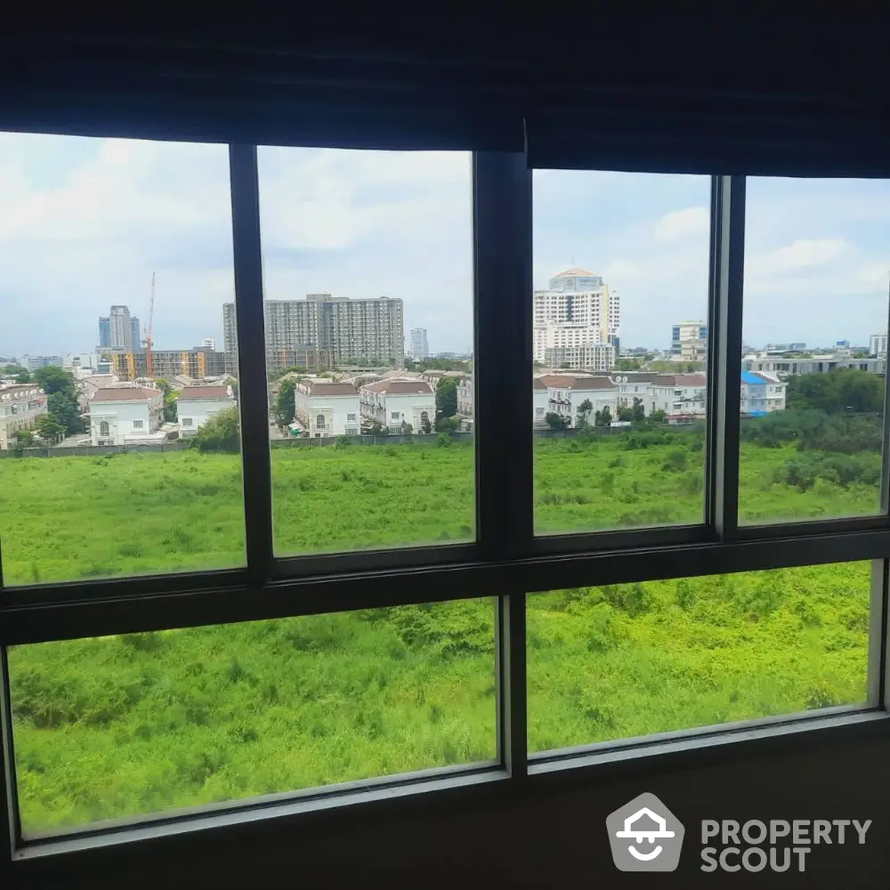 Stunning cityscape view from a large window overlooking lush greenery and urban skyline.