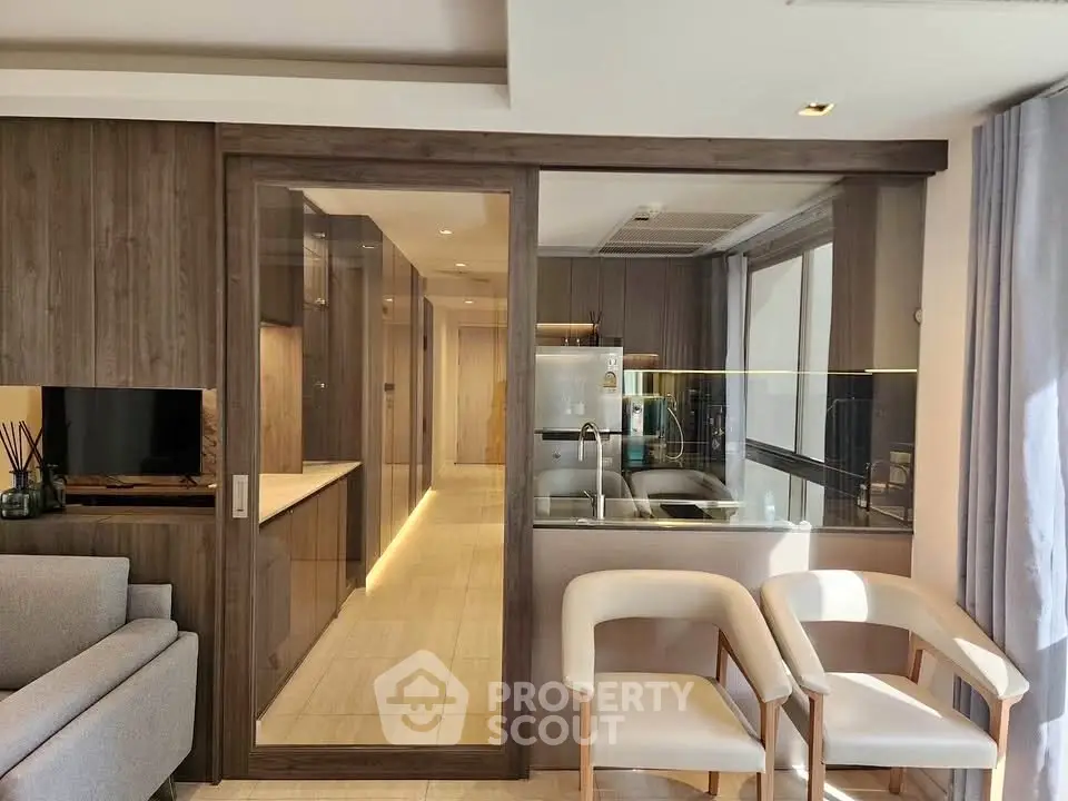 Modern open-plan living room with glass partition and sleek kitchen design