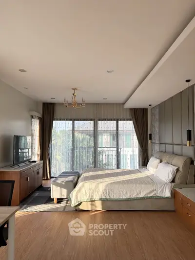 Spacious bedroom with elegant decor and large windows offering natural light