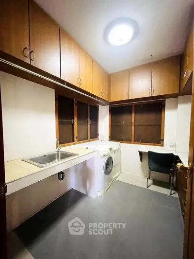 Cozy kitchen with wooden cabinets and washing machine, perfect for compact living.