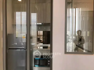 Modern kitchen with sleek appliances and glass partition, featuring a compact design and contemporary style.