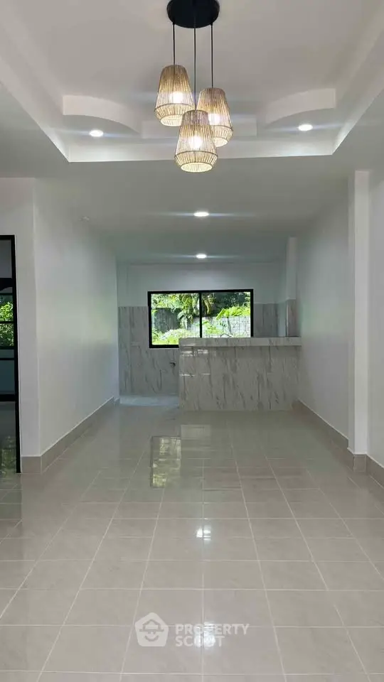 Spacious open layout living room with modern lighting and large window view.