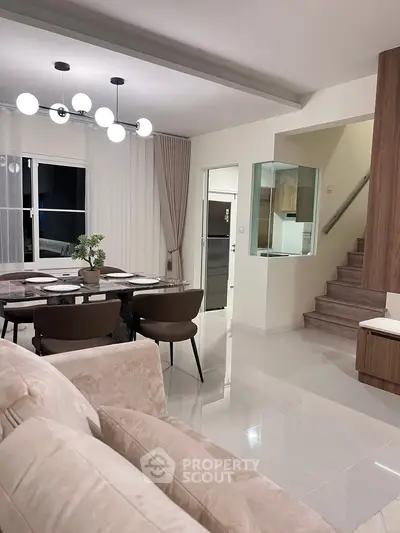 Modern open-plan living room with elegant dining area and stylish lighting.