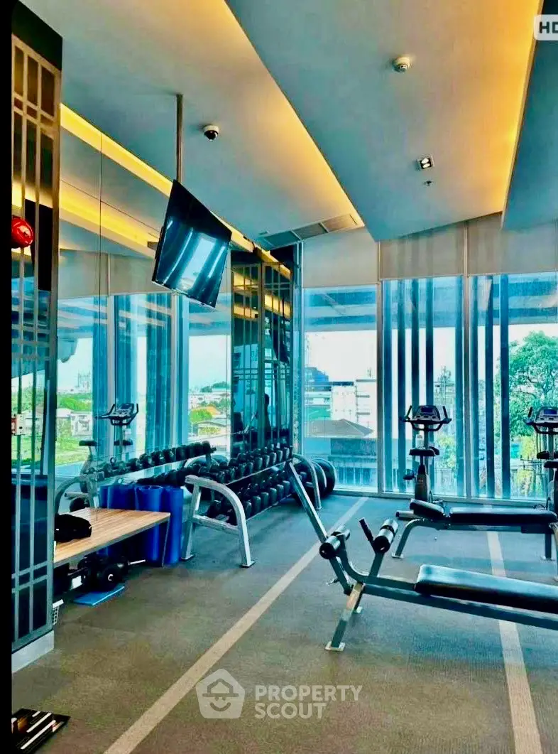 Modern gym with state-of-the-art equipment and city view in luxury building.